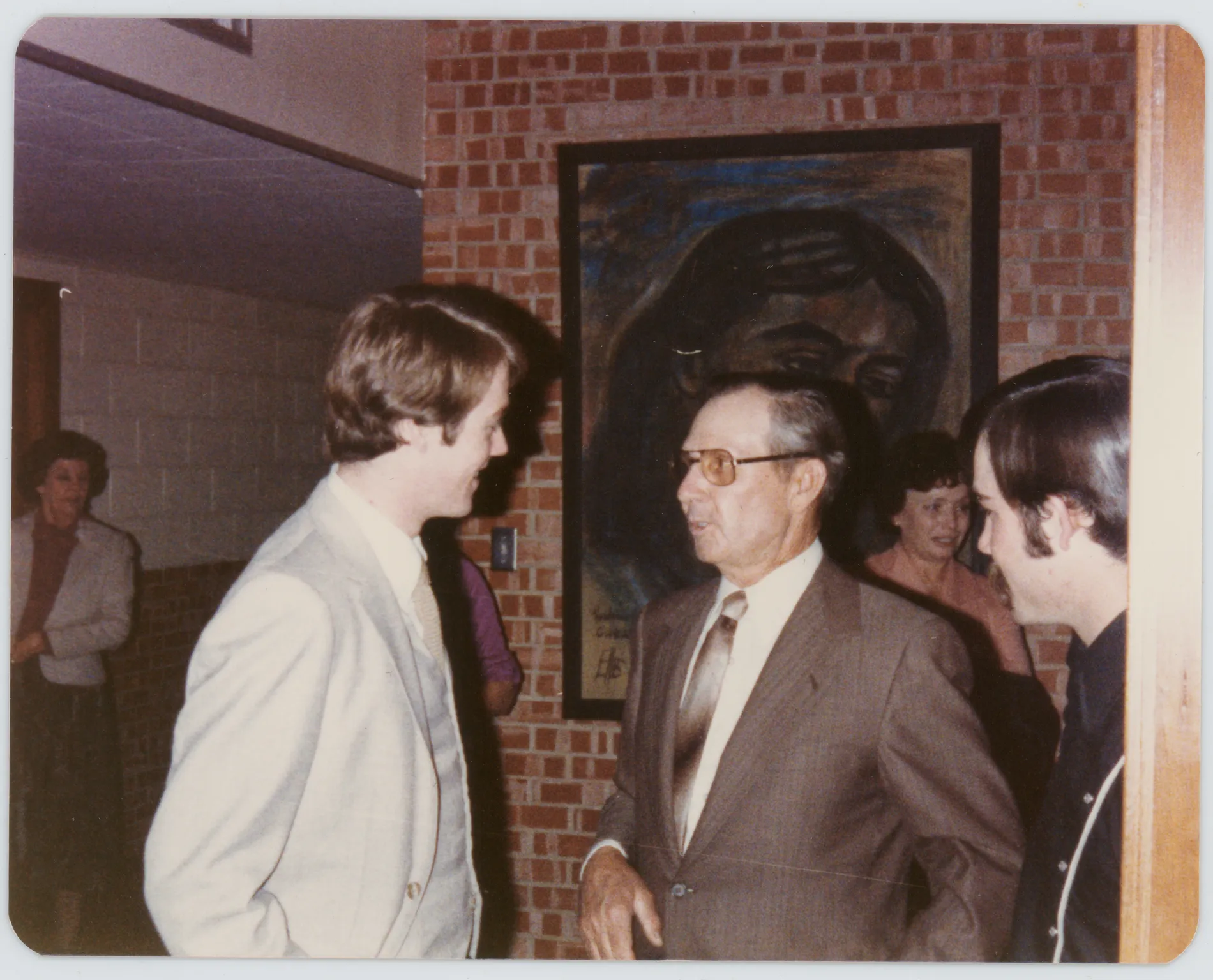 This photograph depicts Harold Allison talking to an unknown man. Verona Grizzle and Jean Allison are in the background.