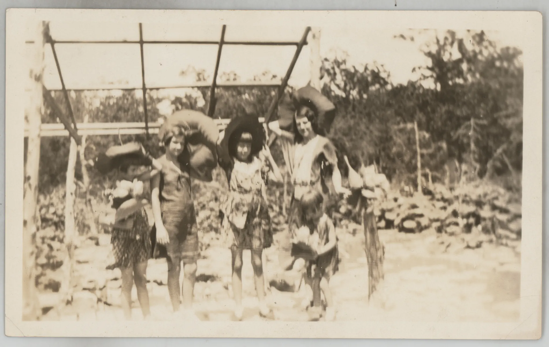 This photograph depicts Loveta, Sammy, Jean, and Mildred McKinstry in unusual outfits with large hats. The location or purpose of this photo is unknown. There is an unidentified girl between Sammy and Jean.