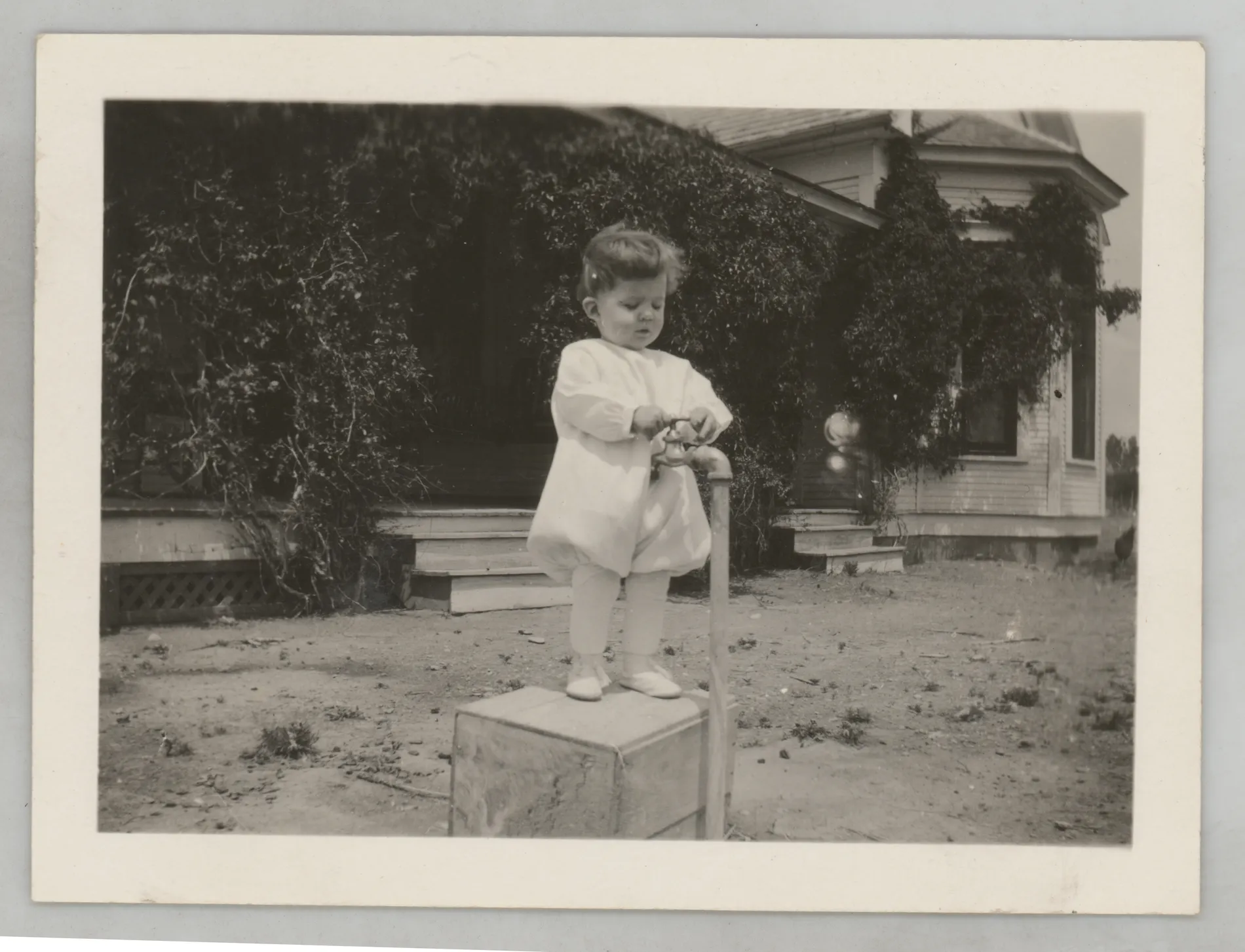 This photograph depicts Sammy McKinstry standing on a box near a box playing with a faucet.