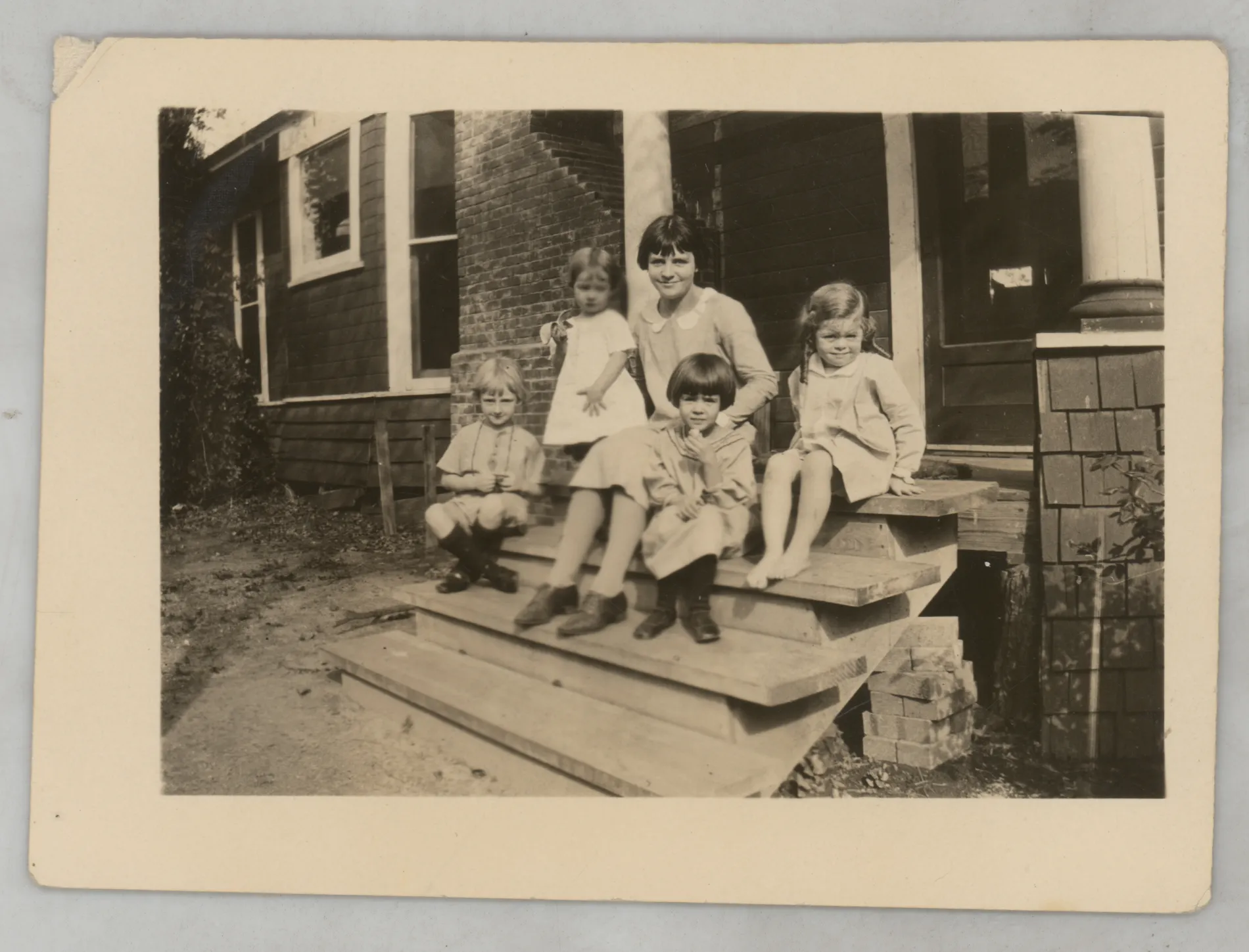 This photograph depicts Sammy McKinstry sitting on a porch with cousin Camille Foster and other Foster and Williamson children at "Aunt Maud's"
