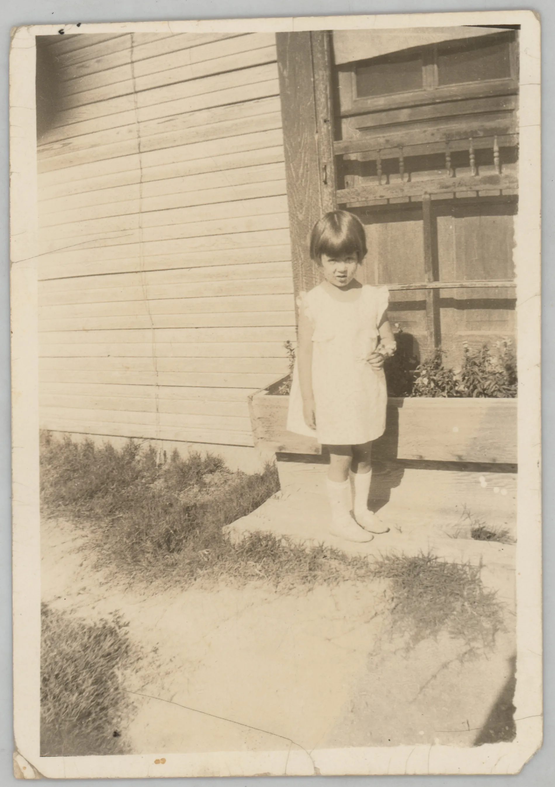 This photograph depicts Sammy McKinstry standing next to a flower bed. She is holding a flower.