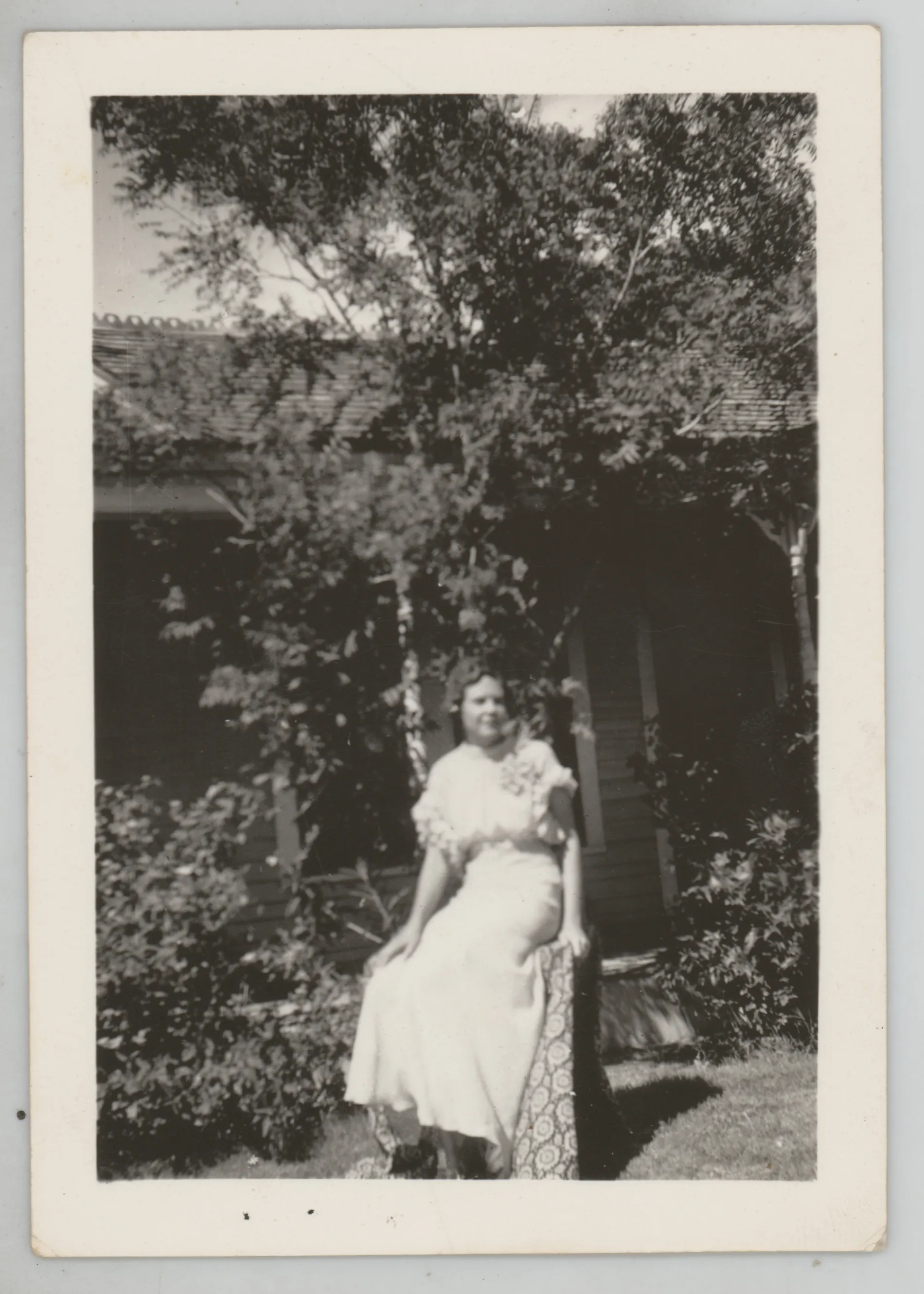 This photograph depicts Sammy McKinstry in a dress sitting outside a house.