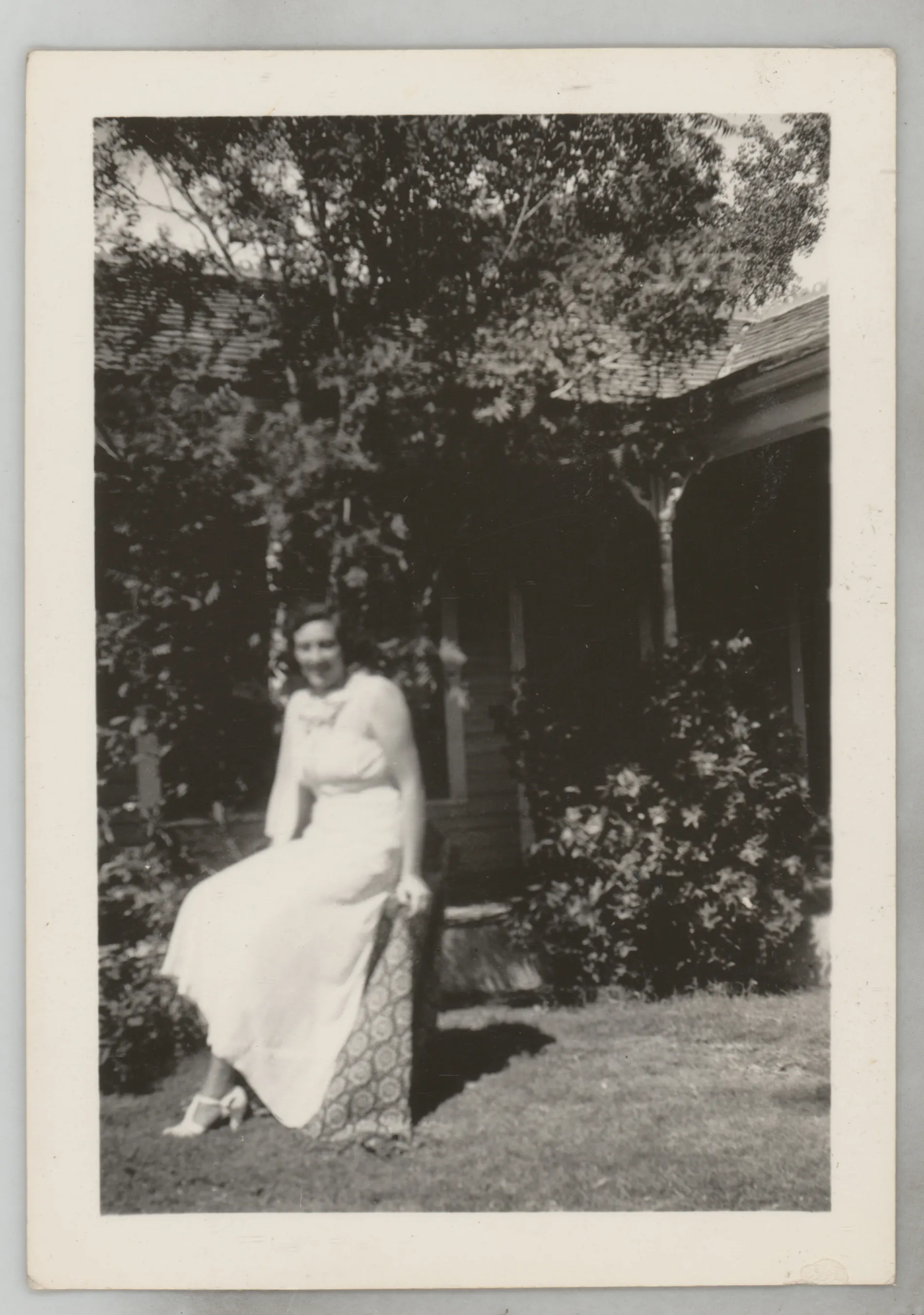 This photograph depicts Sara Beth West in a dress sitting outside a house.