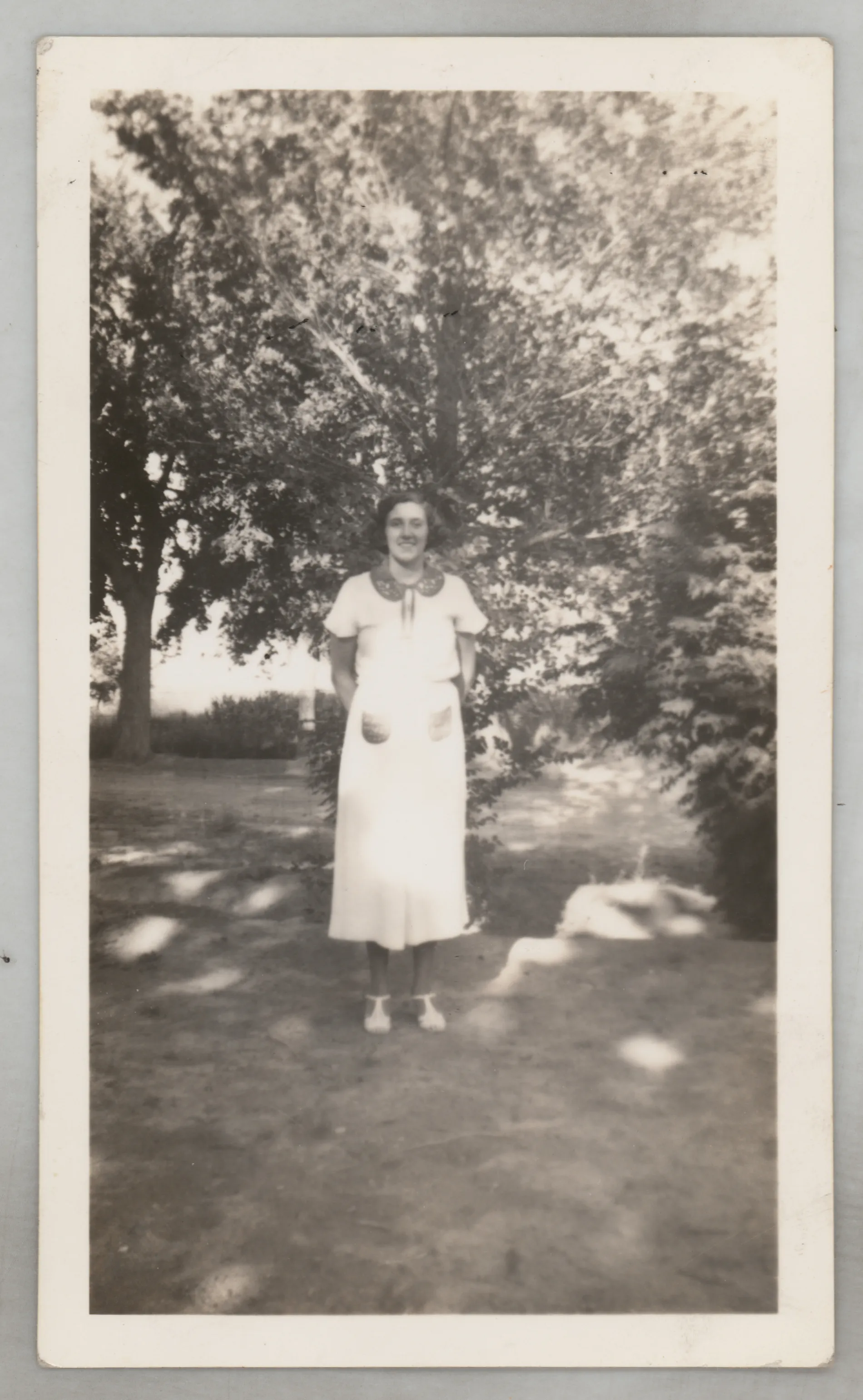 This photograph depicts Sara Beth West in a dress sitting outside a house.