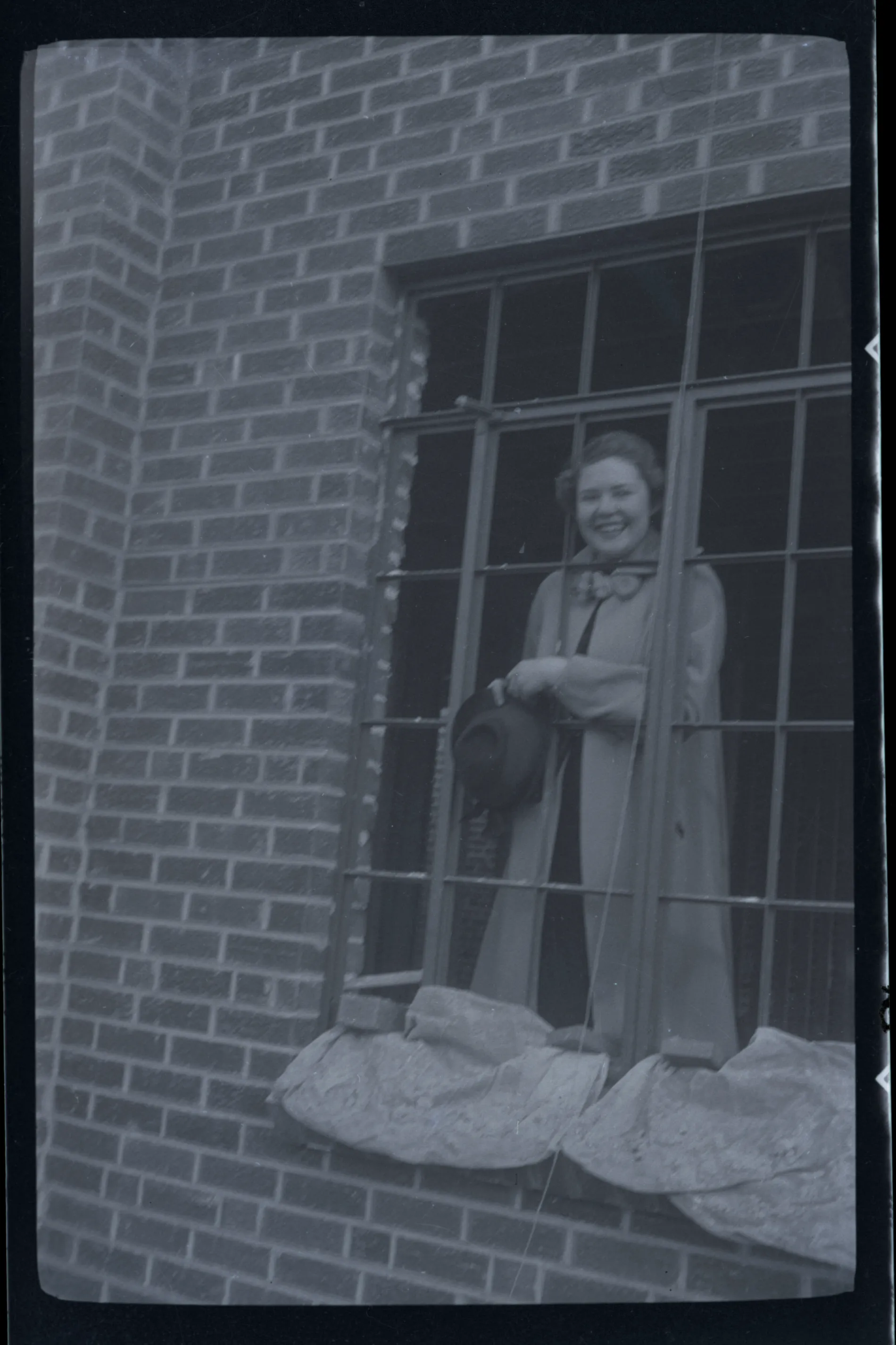This photograph depicts Sammy McKinstry standing in a window holding a hat. This photogrpah may be from Sammy's time in Denver at Colorado Women's College.