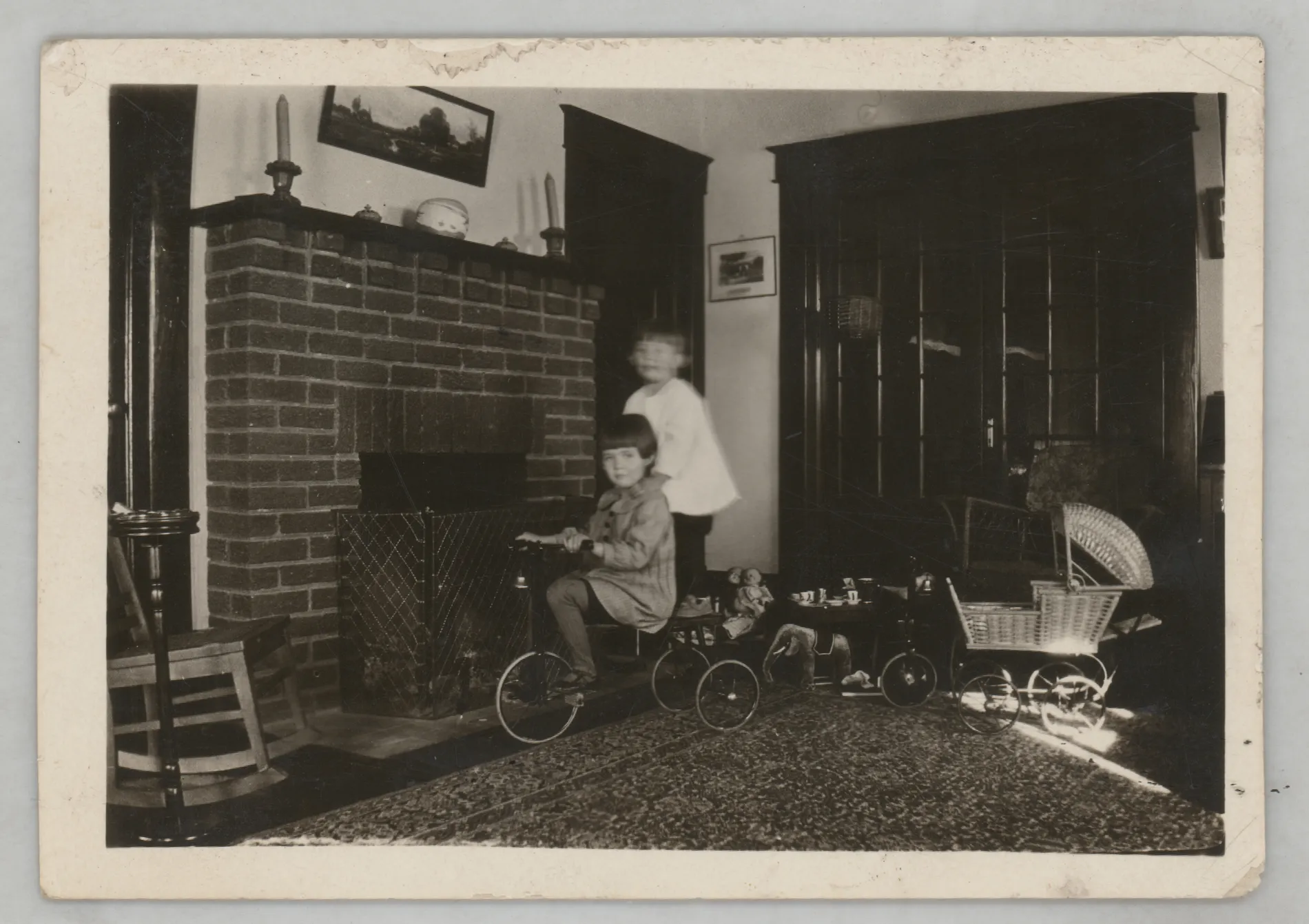 This photograph depicts Sammy and Jean McKinstry riding a tricycle around the living room of their parents' home in Hagerman, New Mexico.