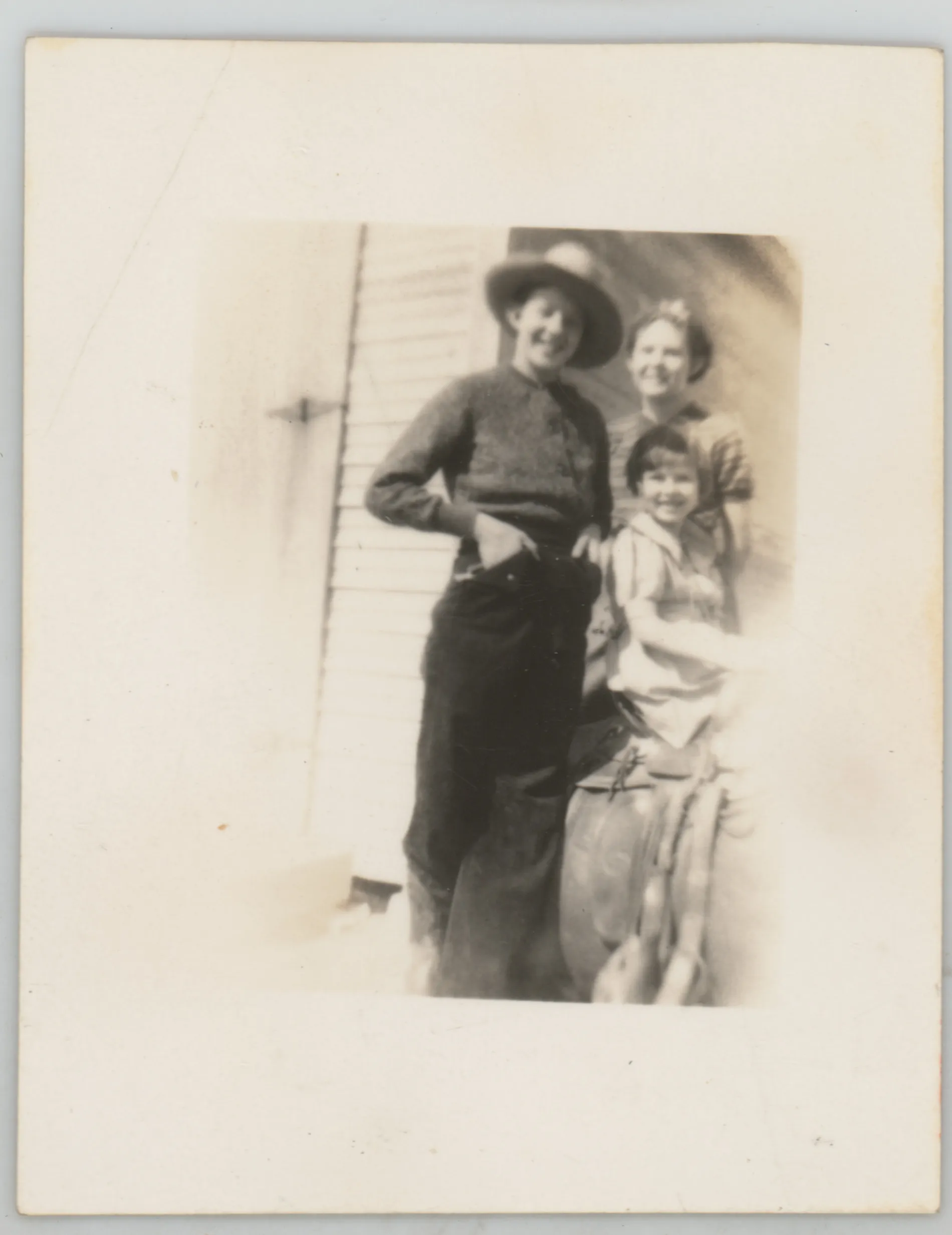 This photograph depicts Sammy, Jean, and Mildred McKinstry standing next to a structure. Jean is wearing a hat.