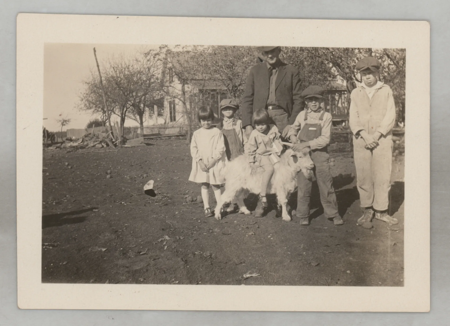 This photograph depicts Sam McKinstry and his daughter, Sammy, standing with four other children near a white goat.