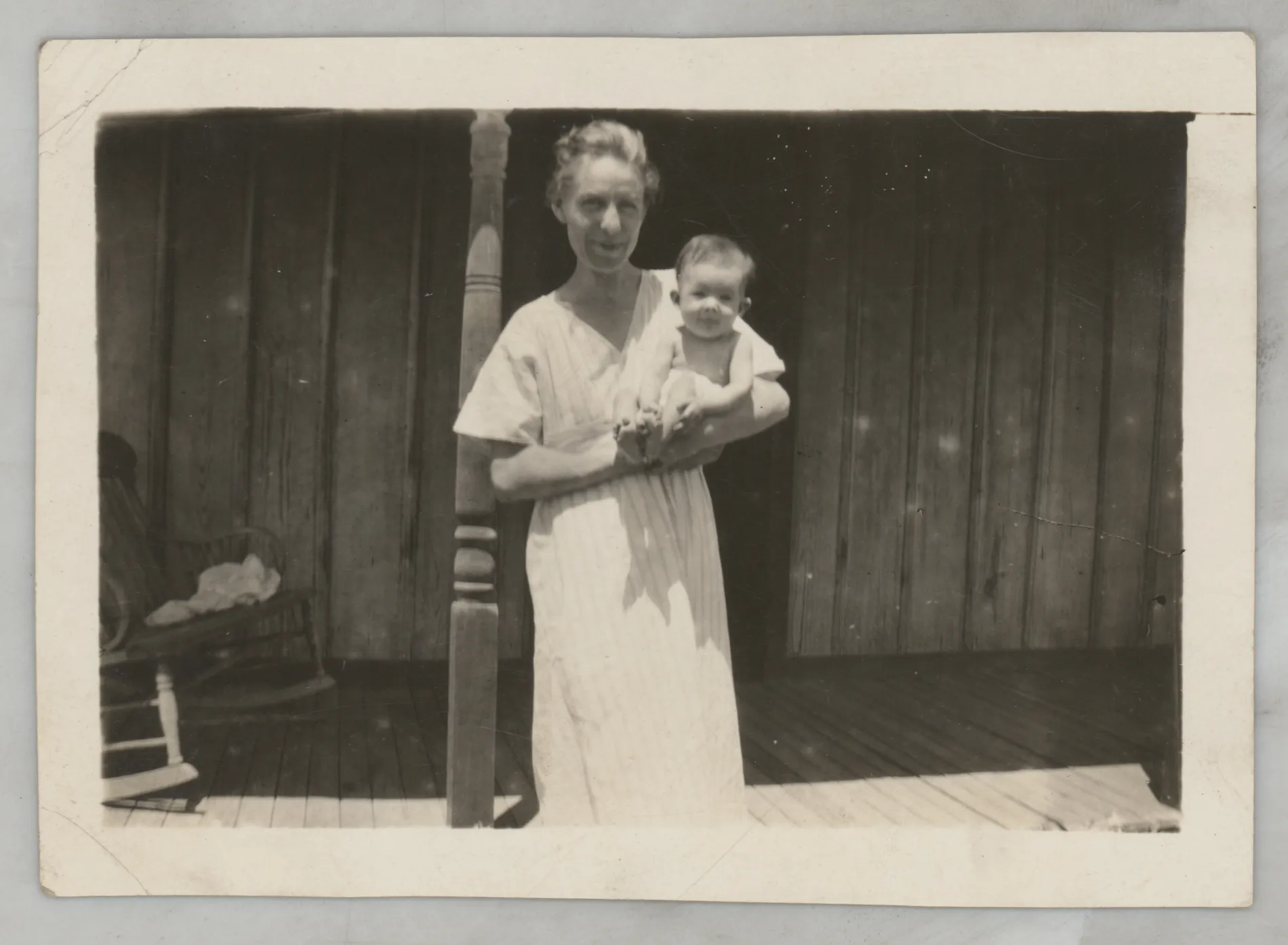 This photograph depicts an unknown woman holding an infant Sammy McKinstry on a porch.