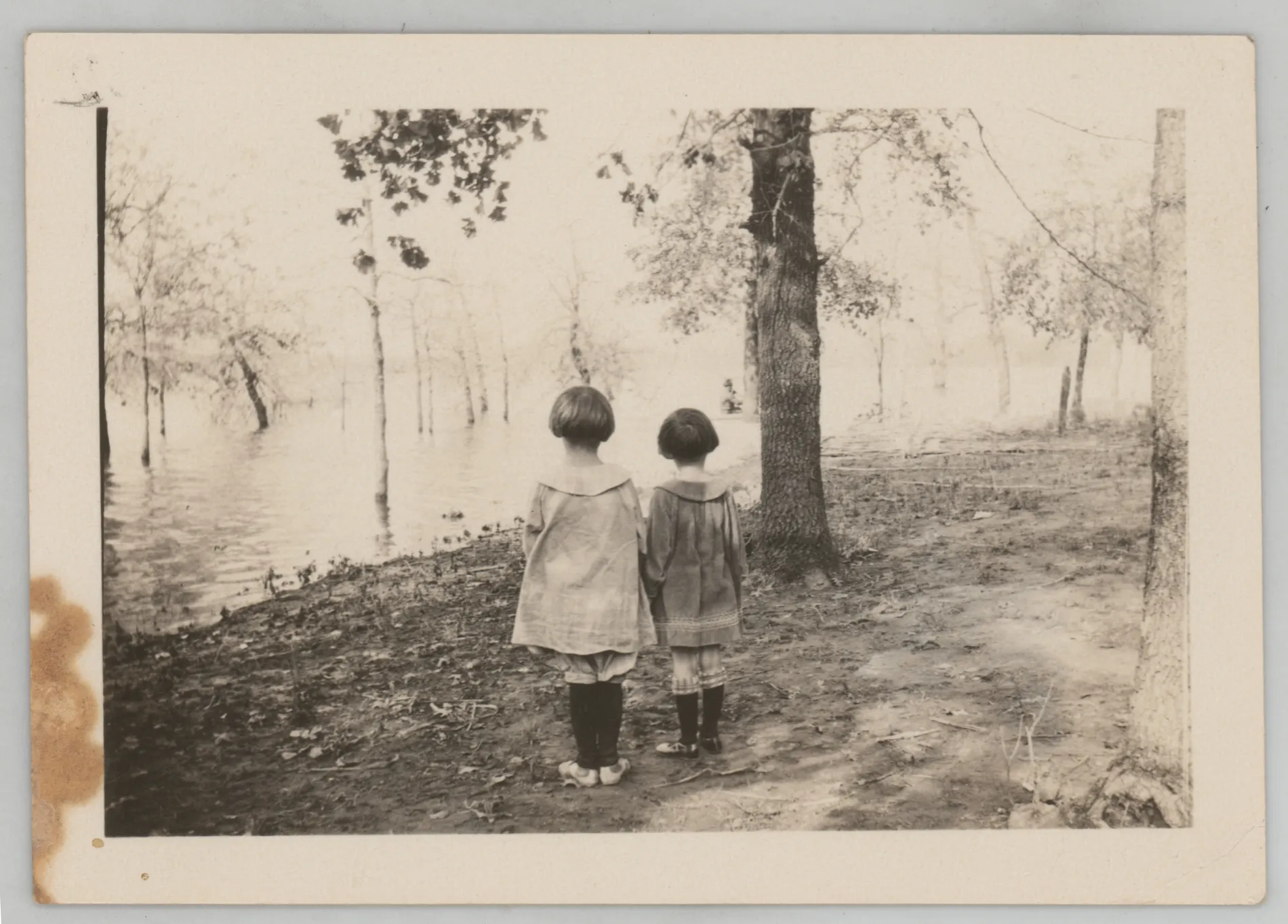 This photograph depicts Sammy McKinstry and her cousin Sara Beth West looking at a flooded area. A boat is in the distance.