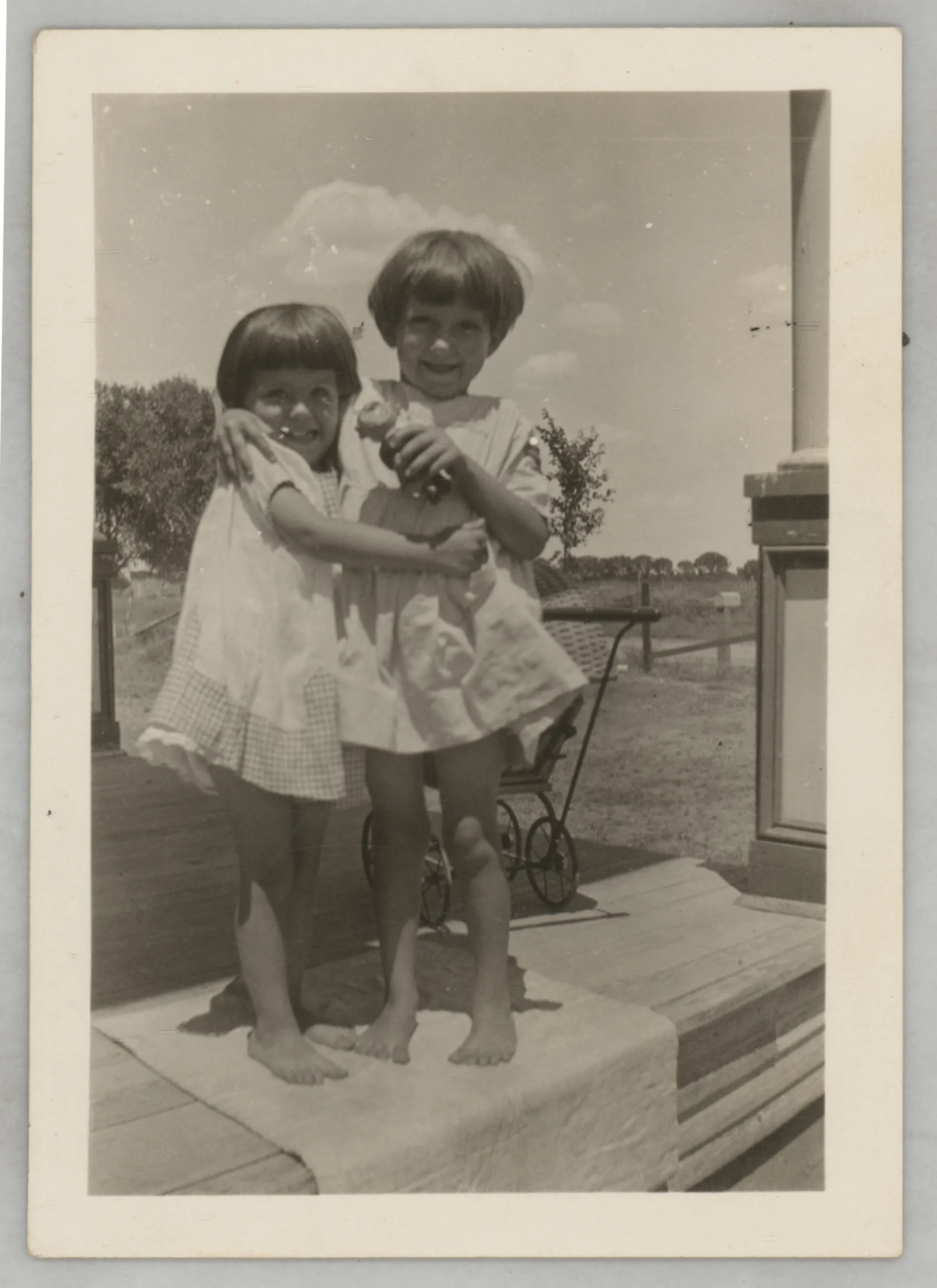 This photograph depicts Sammy McKinstry and her cousin Sara Beth West hugging on a porch.