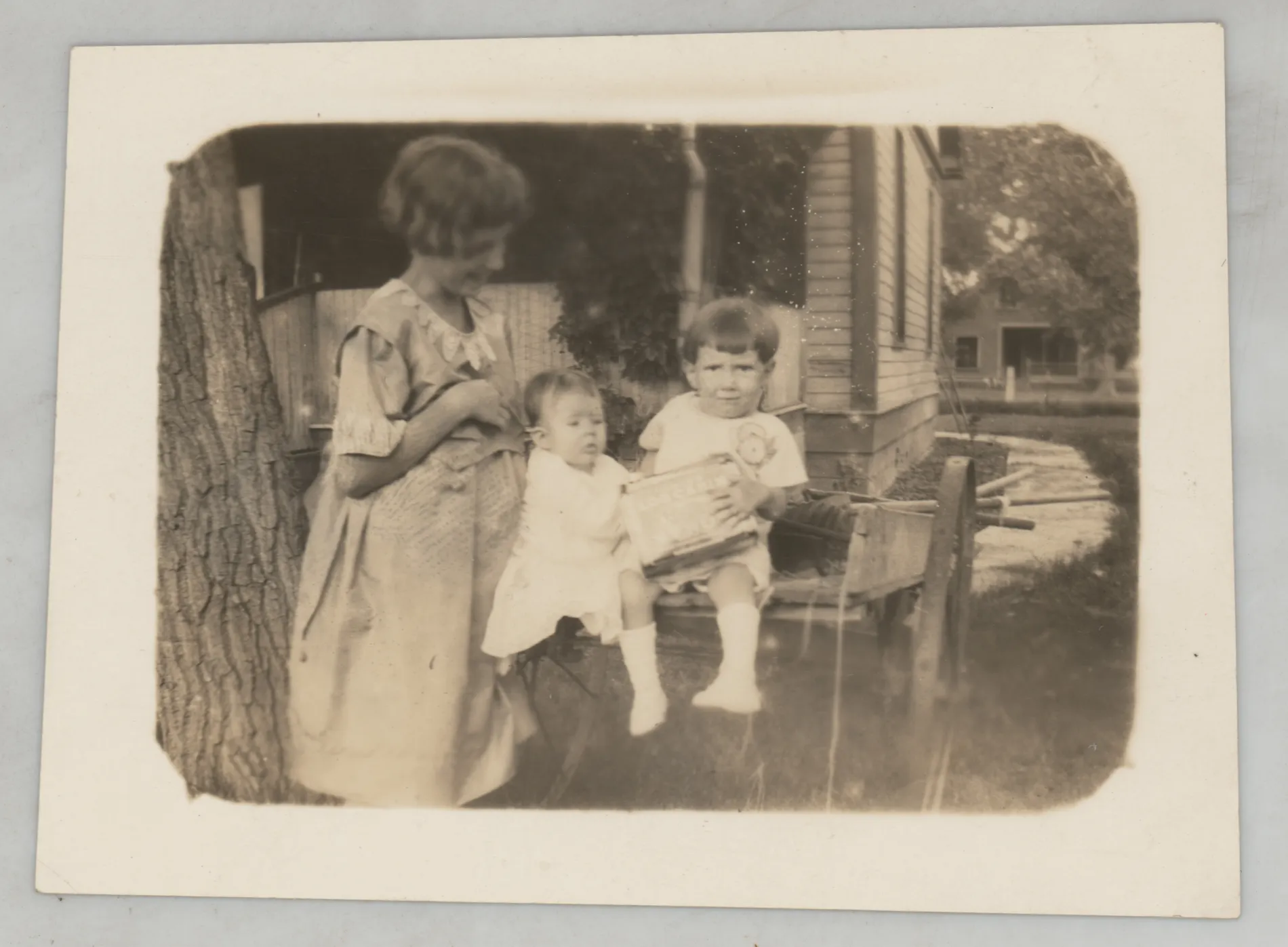 This photograph depicts Sammy McKinstry and her cousin Sara Beth West opening a box of some sort. An unknown older girl is on the left.