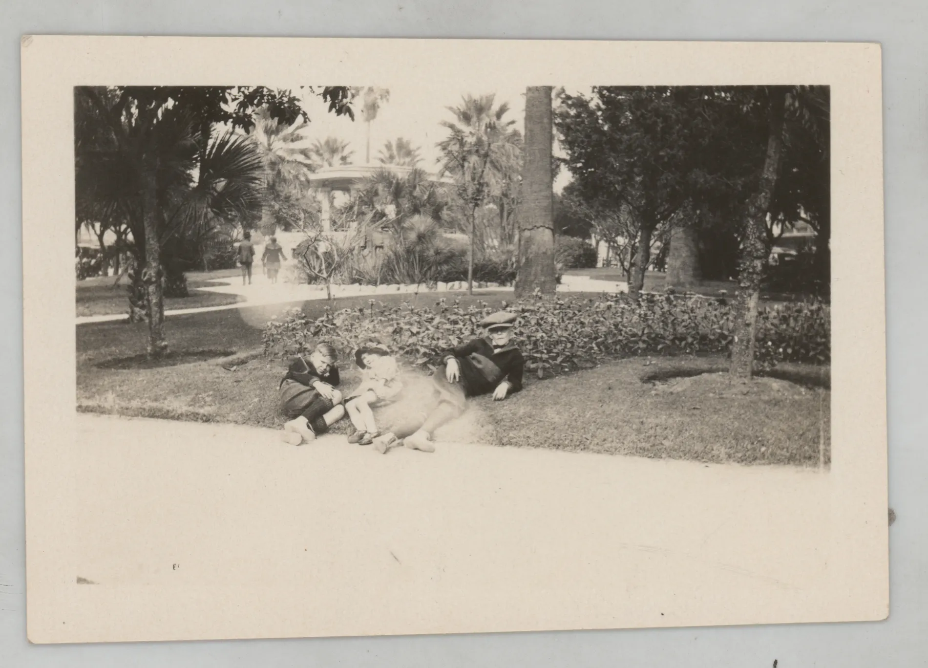 This photograph depicts Sammy McKinstry laying in the grass next to two boys. She is wearing the same attire as she was wearing when at the Alamo (see related image).