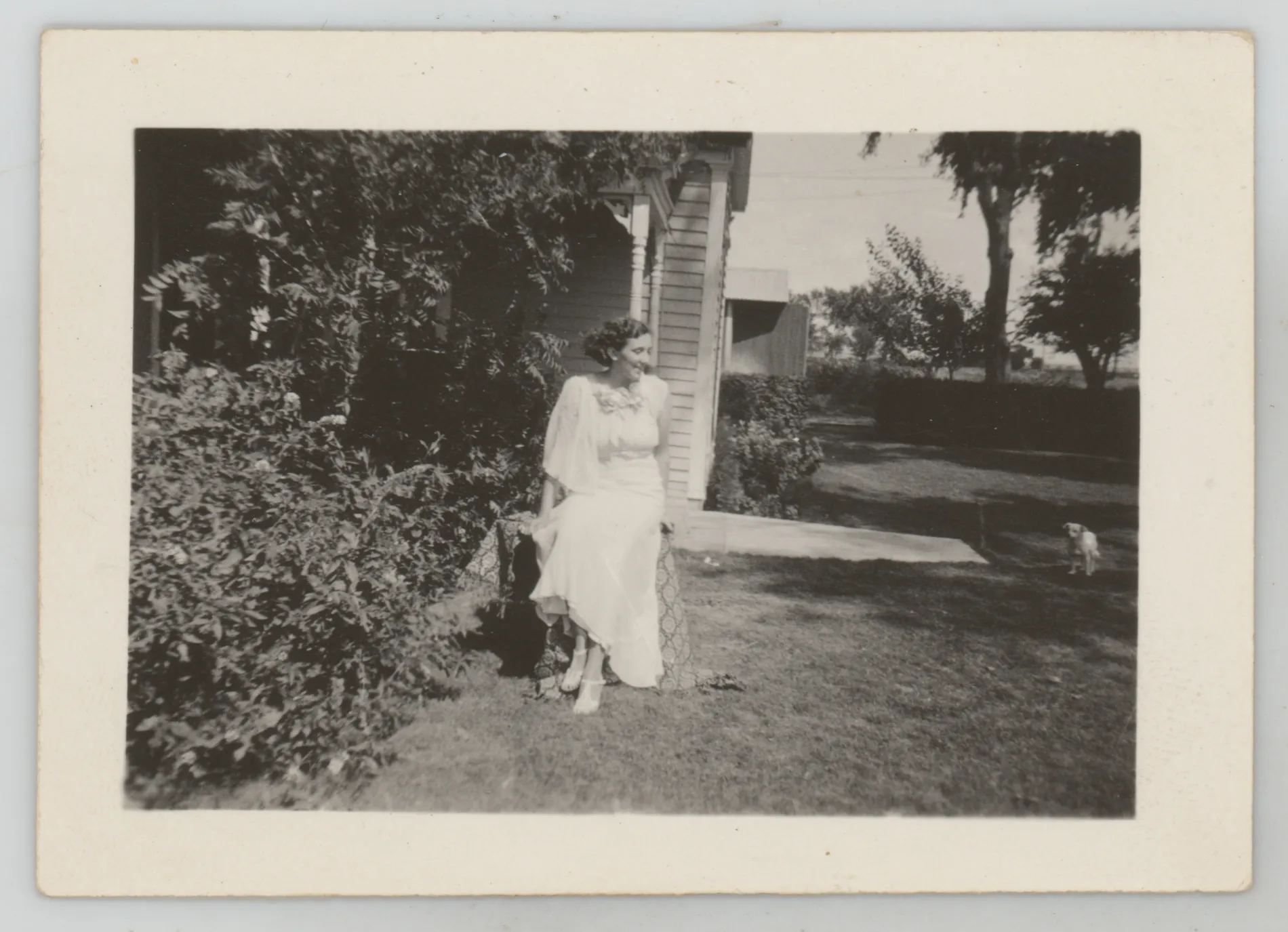 This photograph depicts Sara Beth West in a dress sitting outside a house.