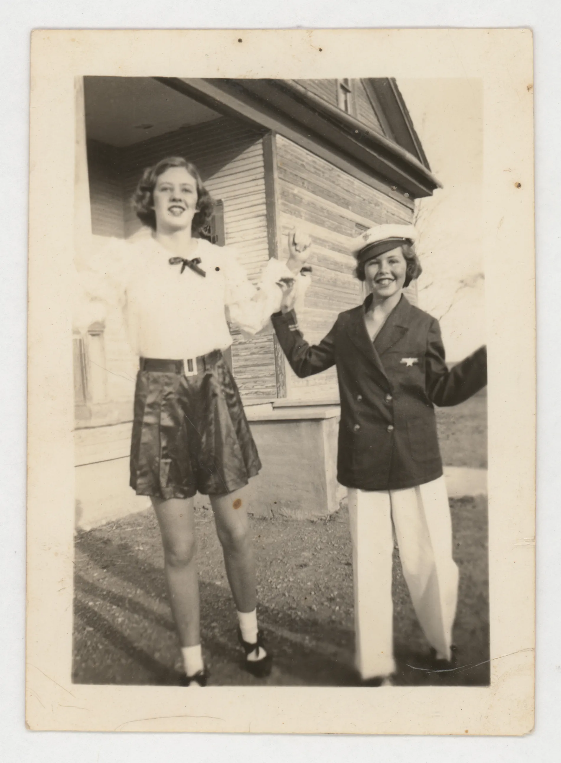 This photograph depicts Jean and Mildred McKinstry dancing or holding hands in front of a house.