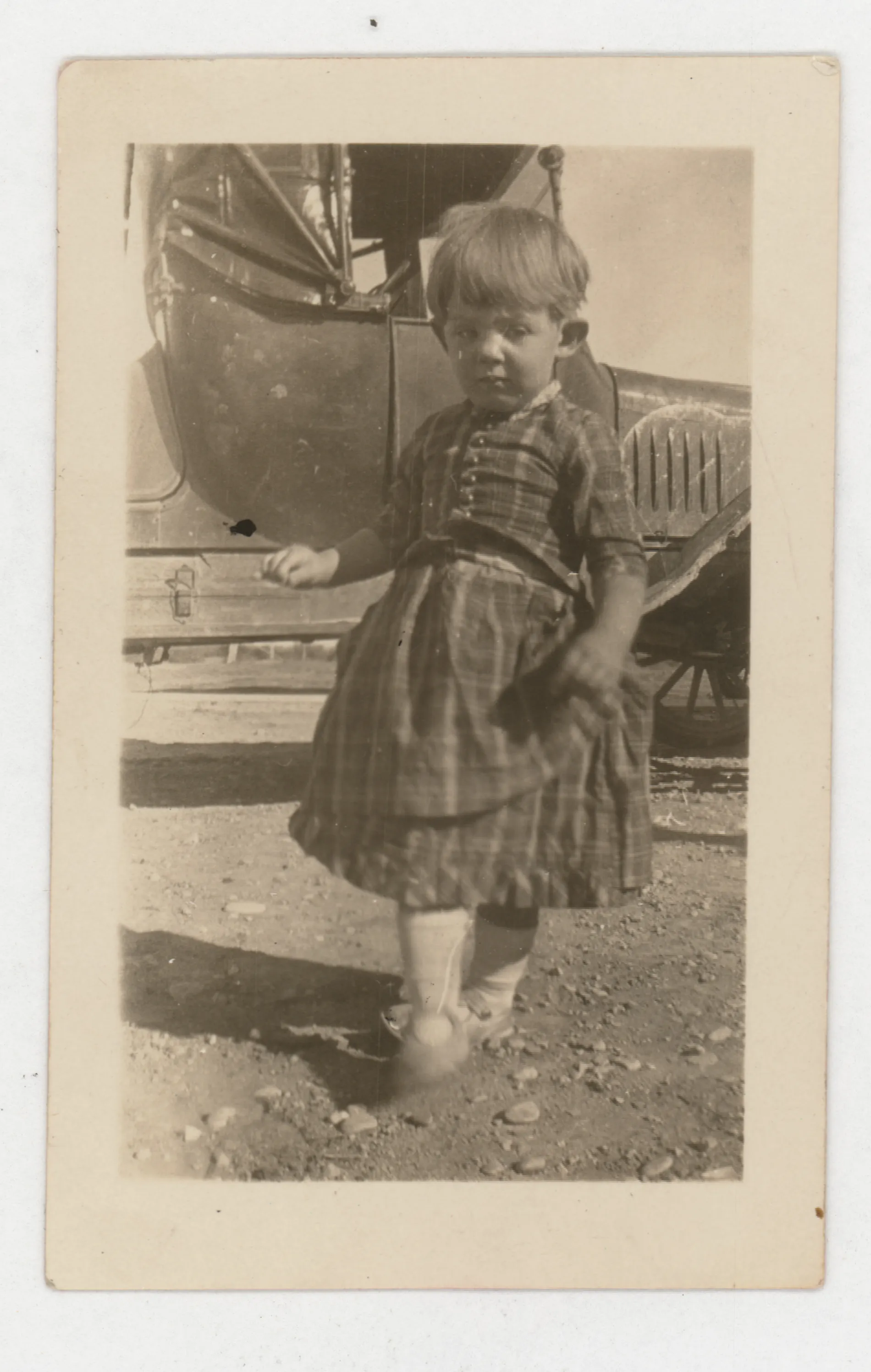 This photograph depicts Jean McKinstry in her mother's dress standing in front of a car.