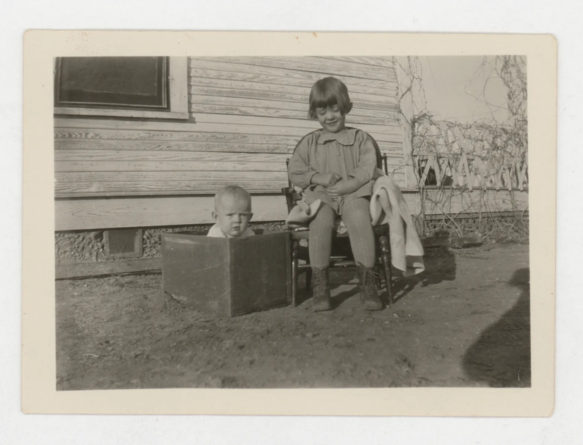 This photograph depicts Jean and Peggy McKinstry. Peggy is the baby in the box and Jean is to the right.