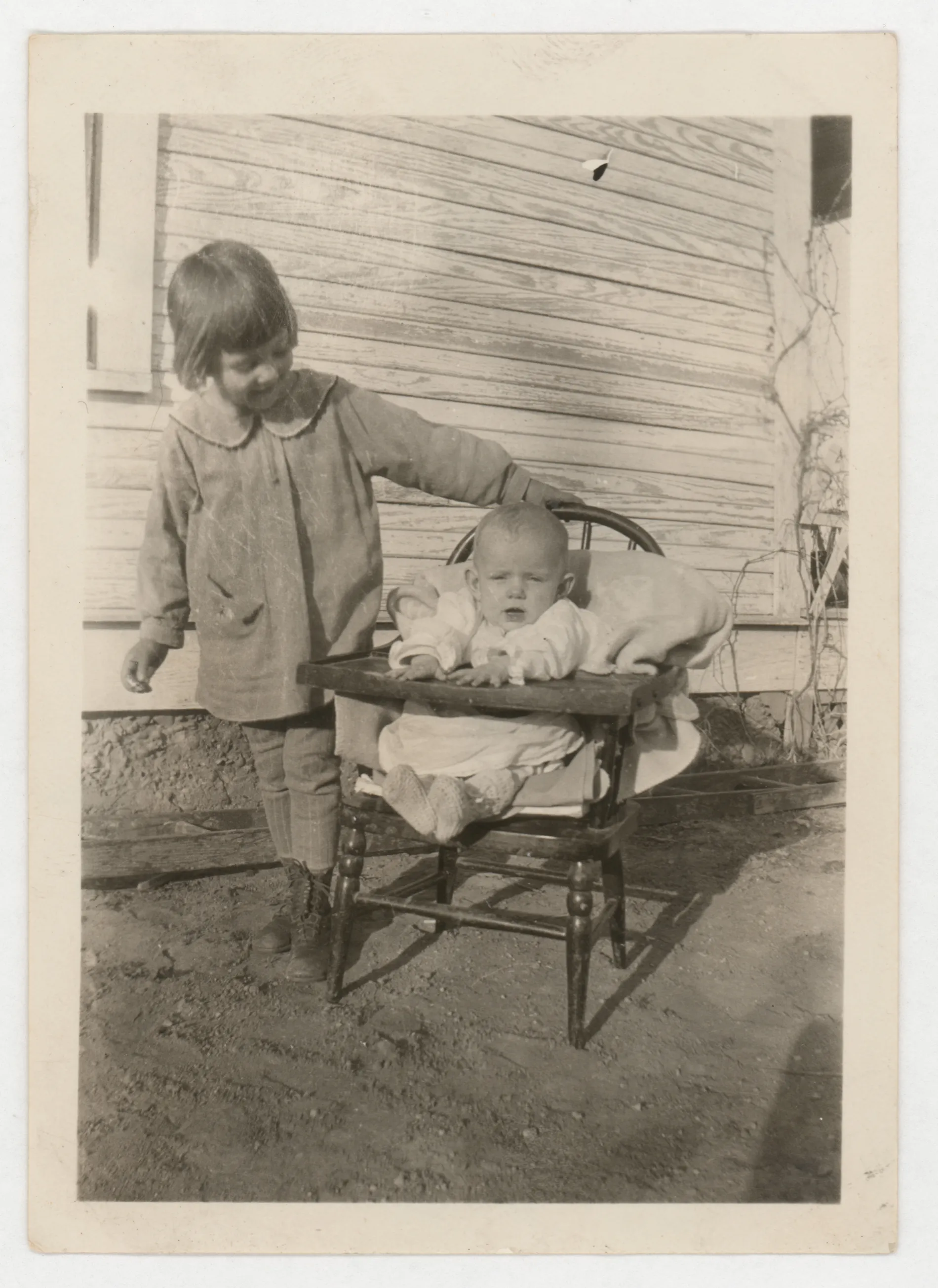 This photograph depicts Jean and Peggy McKinstry. Peggy is the baby in the highchair and Jean is to the left.
