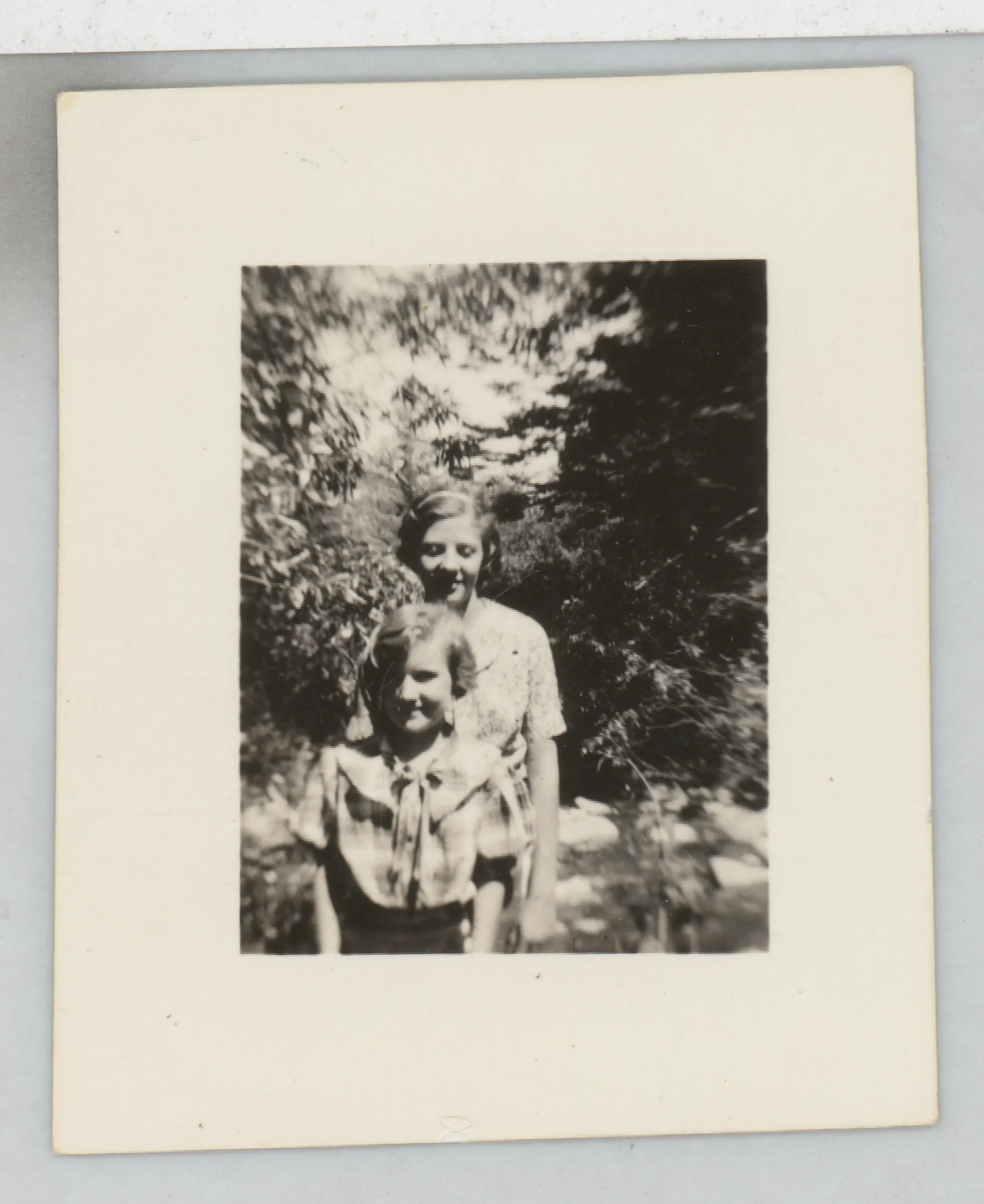 This photograph depicts Jean and Peggy McKinstry standing next to a tree. There is no date on this photograph. There is no location.