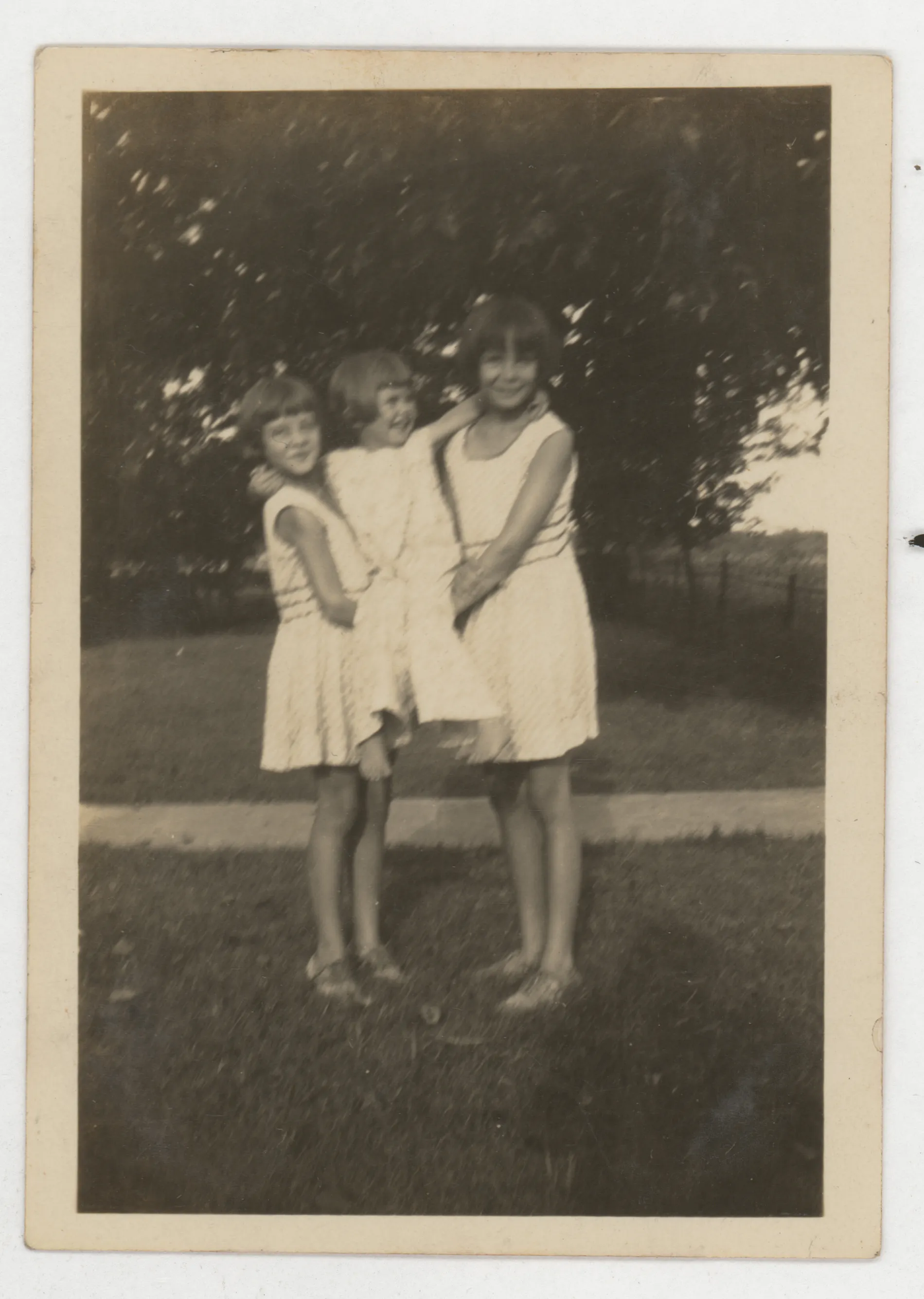 This photograph depicts Jean and Sammy McKinstry holding up their sister Mildred McKinstry in the yard of the home of Charley and Nannie Girdner.