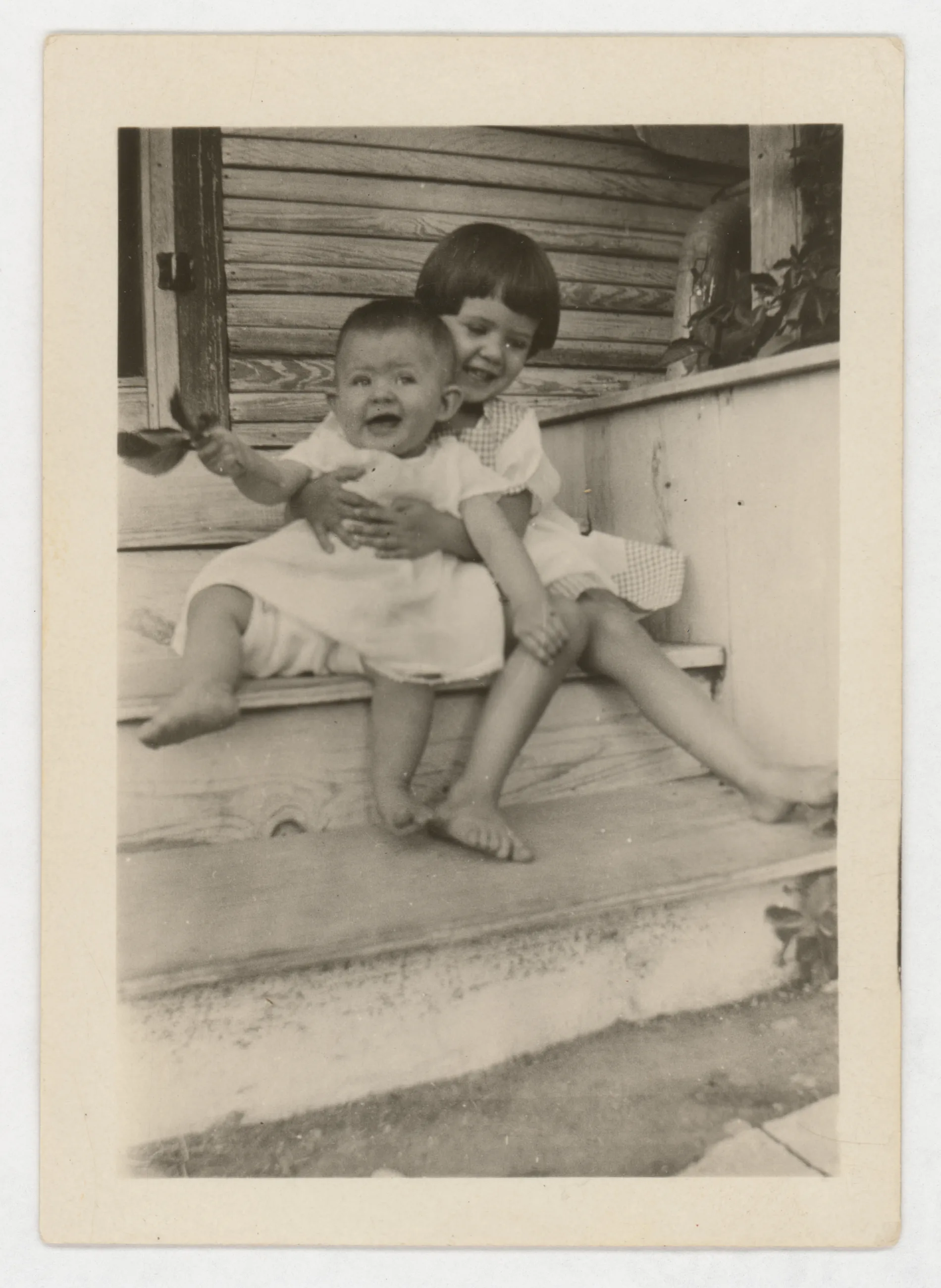 This photograph depicts Sammy and Jean McKinstry on a porch. Sammy is holding Jean.