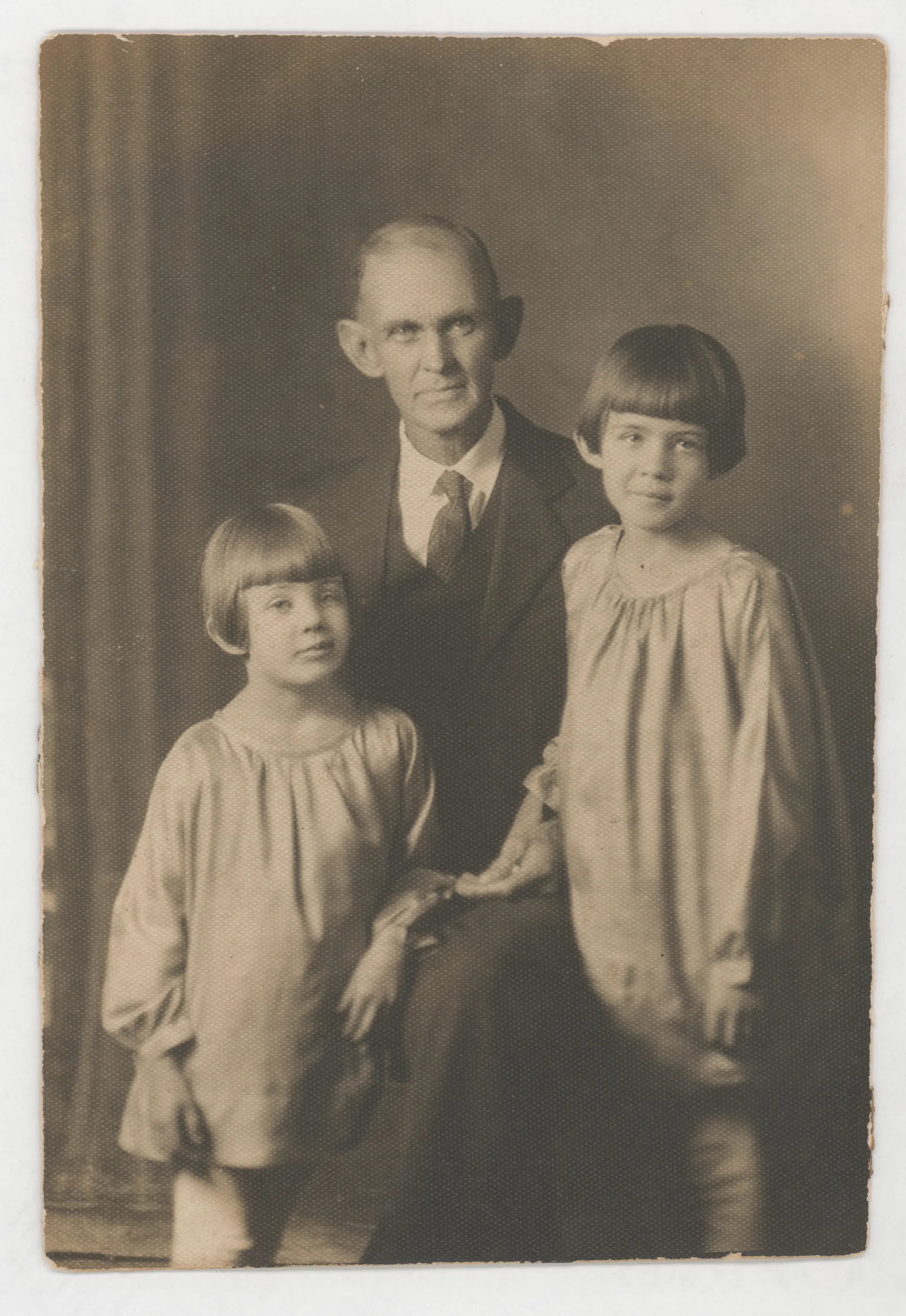 This photograph depicts Austin Swann with his granddaughters Sammy and Jean McKinstry. This photograph was taken in a formal setting just a few years before Austin Swann's death. 