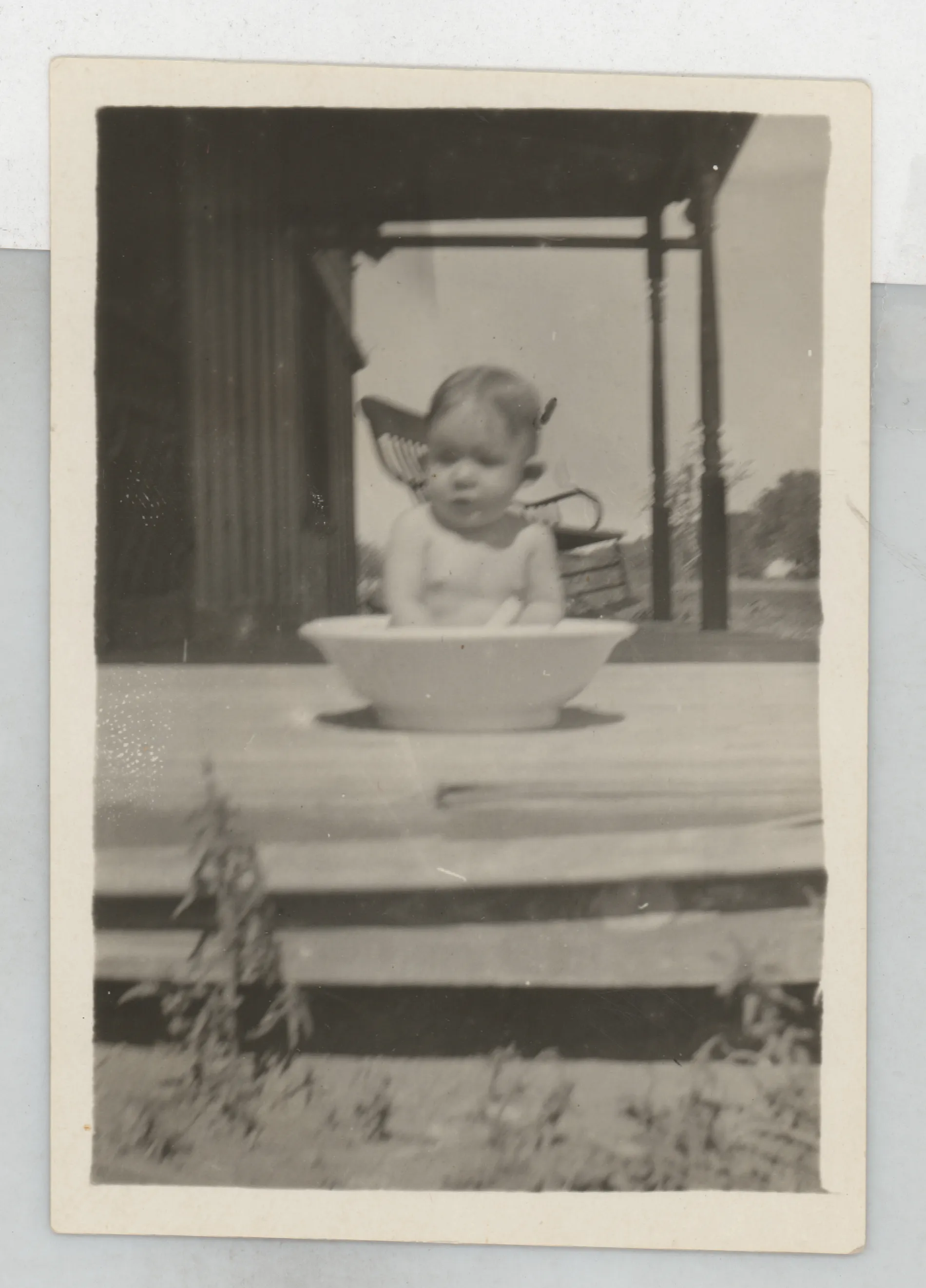This photograph depicts Sammy McKinstry in a small tub on the front porch of a house. The verso suggests this is Jean, but this photograph is also included in an album of Sammy's baby photographs.