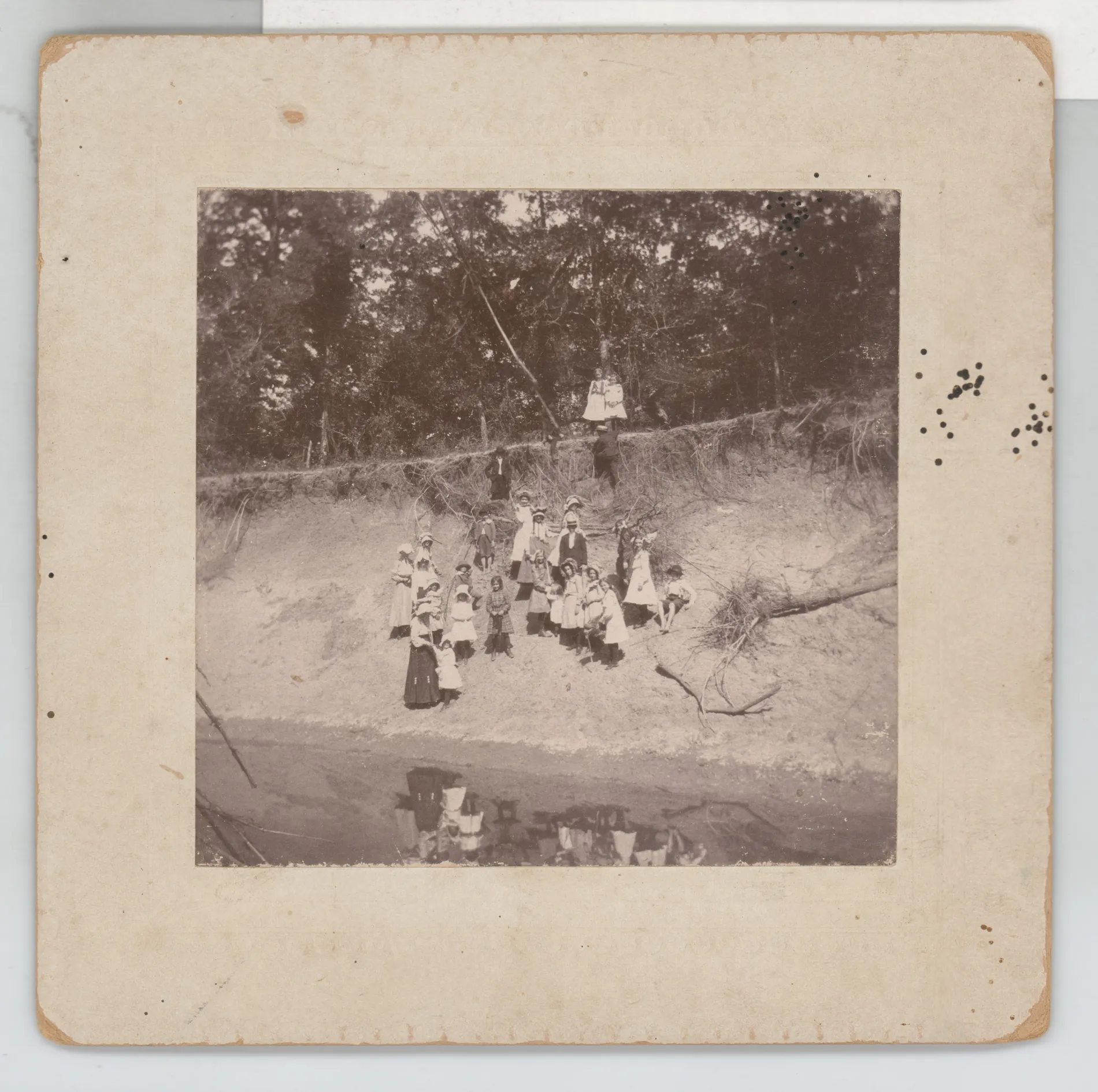 This photo depicts a group of children near the edge of a water source. Some of the children are climbing or descending the edge of the embankment.