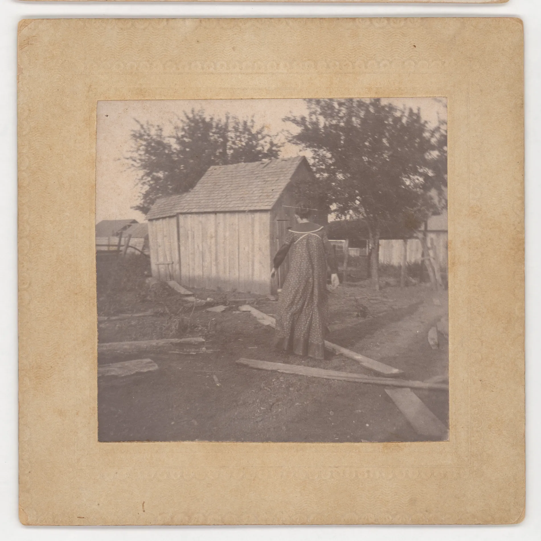 This photograph depicts Nannie Swann Girdner walking to an outhouse.