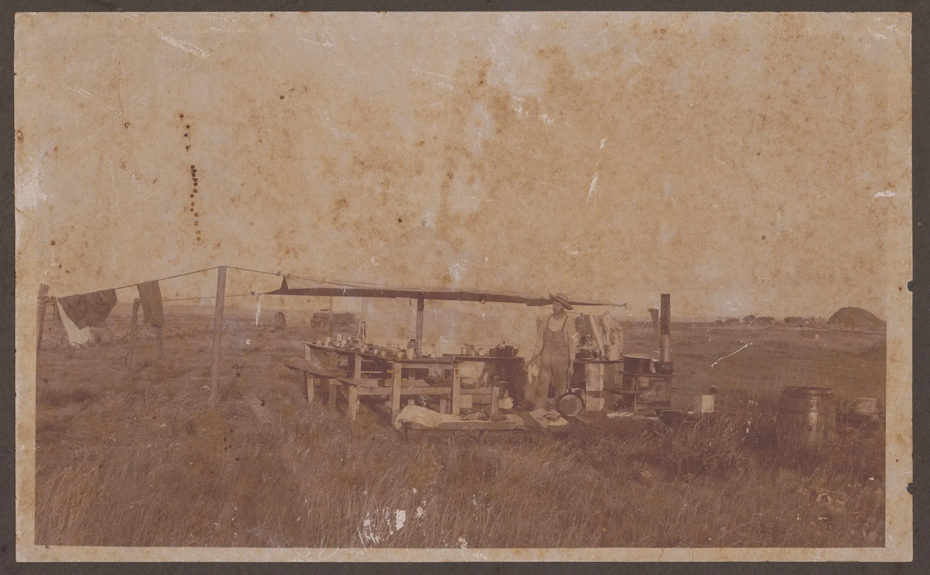 The Swann, Girdner & Swann cooking outfit. The tent contains a stove, pots, pans, and other cooking utensils. Although not noted, John Swann stands holding a pan.