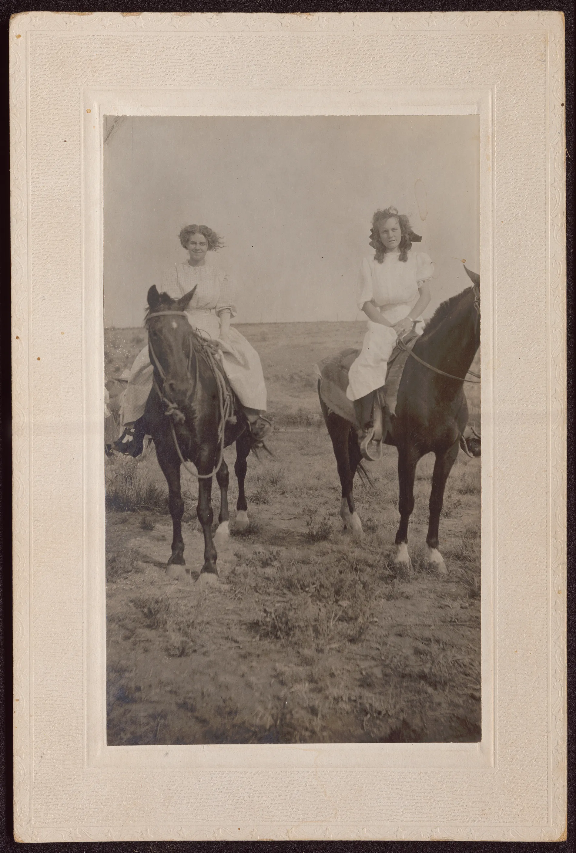 The photograph depicts Loveta Swann (left) and Mae McCoy (right) riding horses in Hagerman, New Mexico.