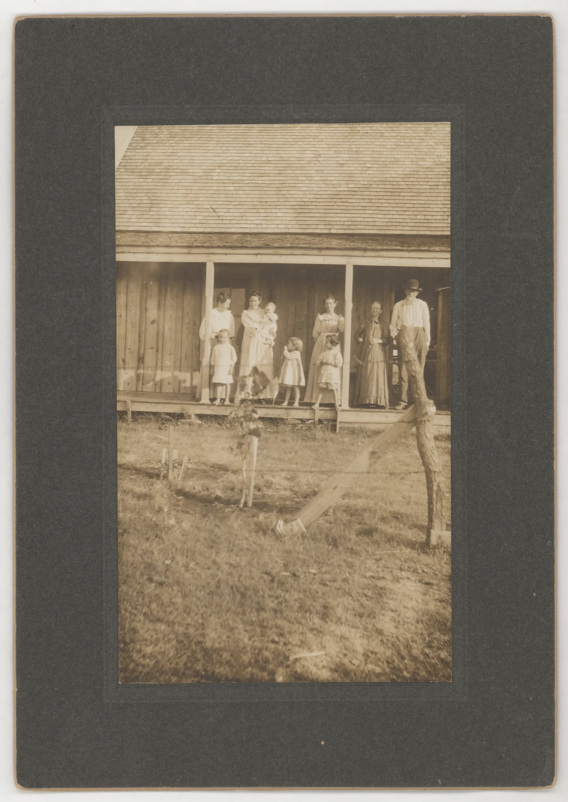 A photograph of the Ben and Minerva Thomas family in front of a structure with other unidentified people. 'Aunt Matt' is supposed to be in this picture, but she is not identified. Two other women are present, as well as four unidentified children. One of the children may be Loveta Swann, a granddaughter of Ben and Minerva.